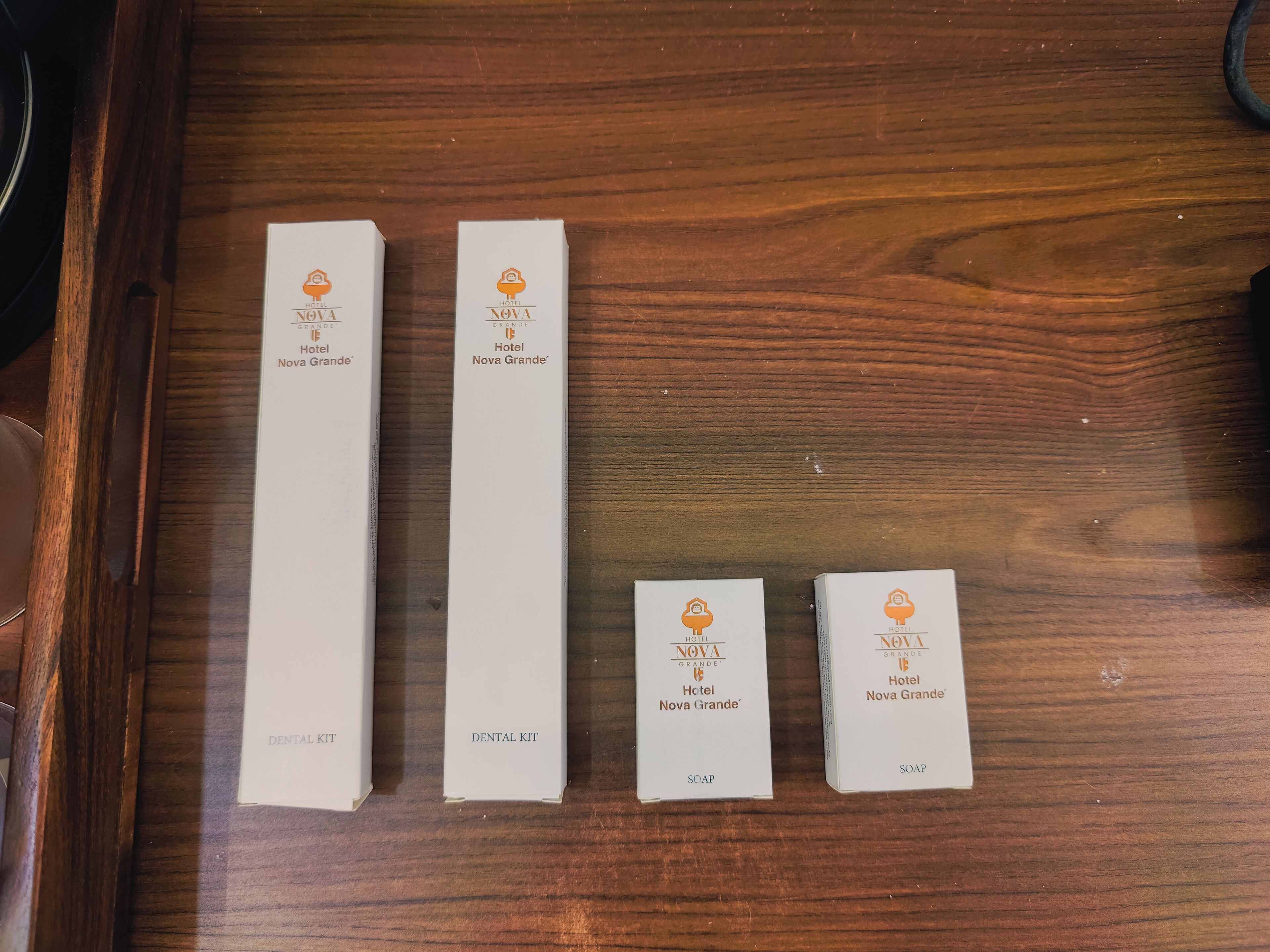 Vier dozen tandverzorgingssets van Hotel Nova Grande op een houten oppervlak.