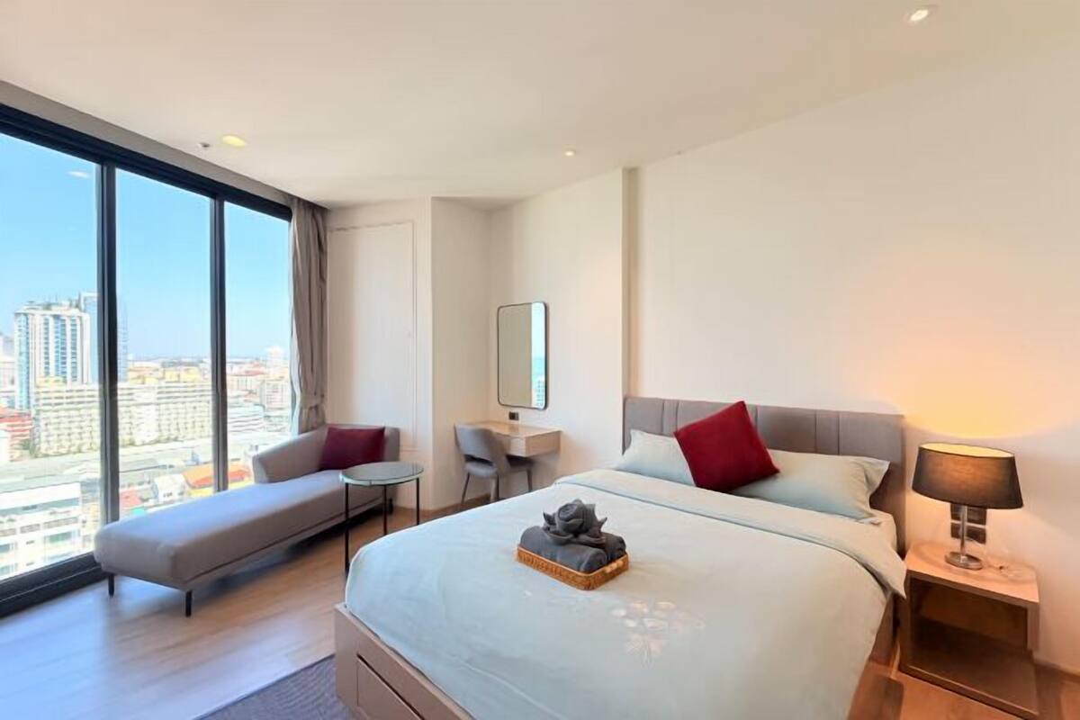 Une chambre d’hôtel moderne avec un grand lit, un bureau, une chaise et une vue sur la ville.
