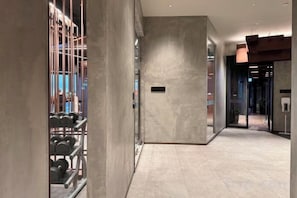 A hallway with a modern design, featuring a metal rack of dumbbells, a large grey wall, and a door leading to another room. - EDGE Central Pattaya Oasis (Pattaya)