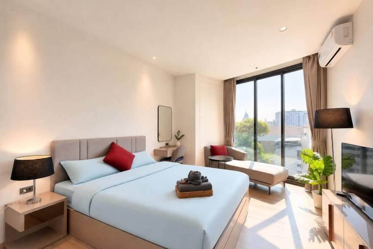 Une chambre d’hôtel moderne avec un grand lit, des tables de chevet, une télévision et une vue sur la ville.