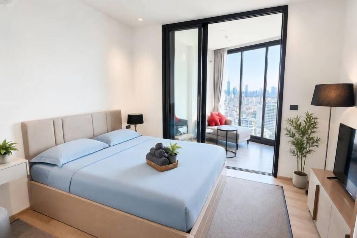 Une chambre d’hôtel moderne dotée d’un grand lit, d’une télévision, d’un bureau et d’un balcon offrant une vue sur la ville.