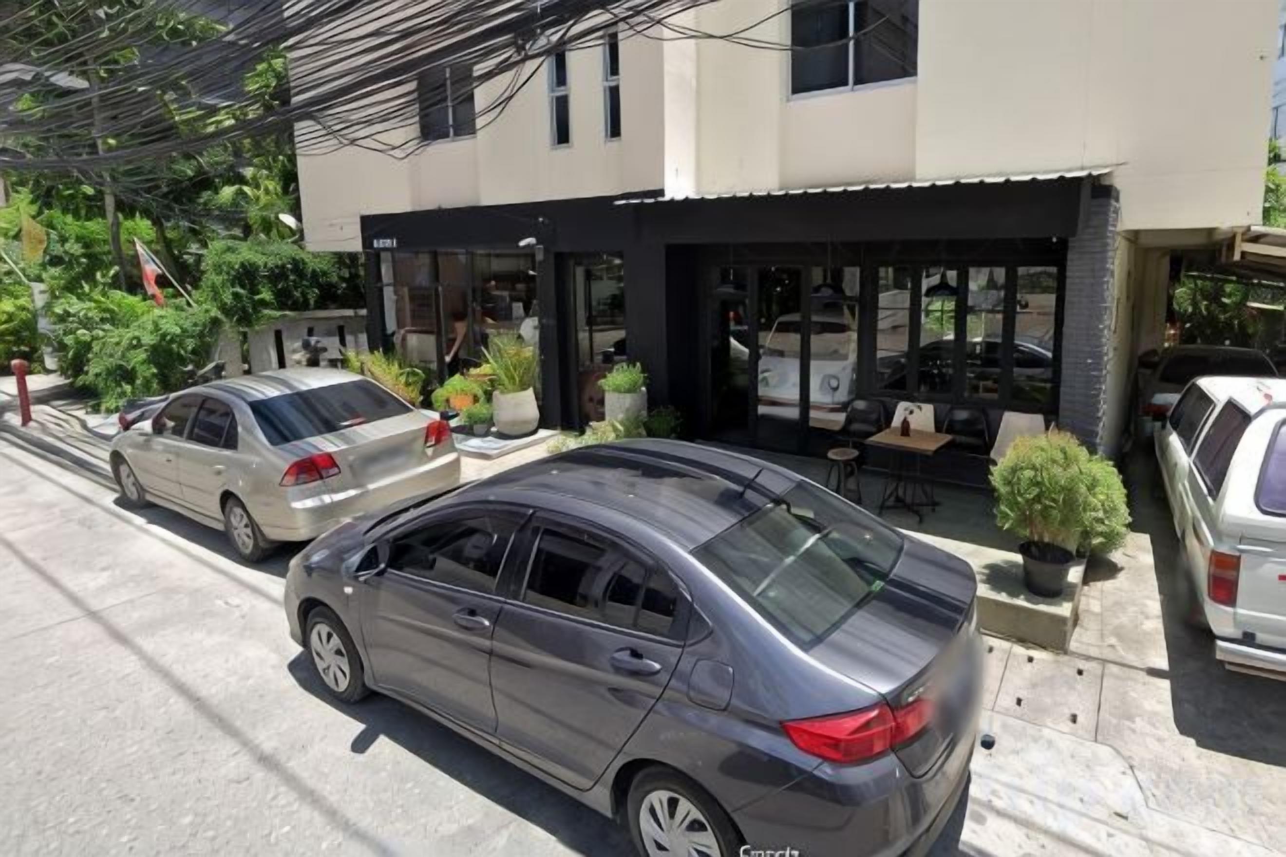 A two-story building with a covered outdoor seating area and a car parked in front.