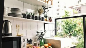 Une cuisine avec des carreaux blancs, un four noir et une fenêtre donnant sur un paysage verdoyant.