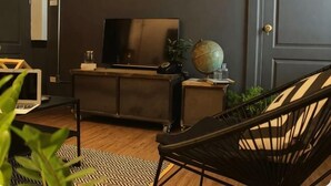 Un salon moderne avec un mur de couleur sombre, un téléviseur à écran plat, un globe terrestre et un fauteuil noir.