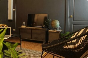 A modern living room with a dark wall, a flat-screen TV, a globe, and a black chair. - The Ombra Small House No.4 (Chiang Mai)