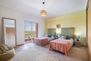 A bedroom with two beds, a balcony, a sofa, and a patterned rug. - Villa 'Picota' with Sea View, Wi-Fi and Air Conditioning (Tavira)