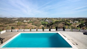 Et rektangulært swimmingpool med en klar blå vandoverflade, omgivet af en belagt terrasse.