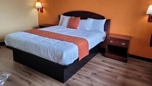 Quarto de hotel com uma cama grande, cabeceira de madeira, duas mesas de cabeceira e um criado-mudo.
