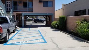 Uma área de estacionamento com uma placa de 'Proibido Estacionar' e um edifício com varanda.