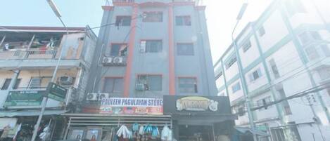 Un edificio de varios pisos con una planta baja comercial que incluye una tienda llamada 'PAULEEN PAGULAYAN STORE' y un letrero que dice 'TAPAS'.