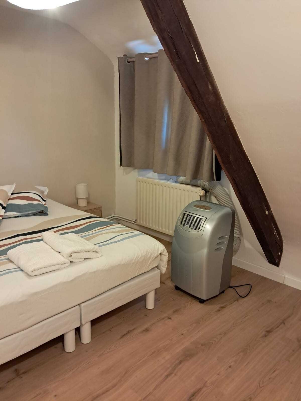 Een slaapkamer met een bed, een radiator, een kachel en een raam met gordijnen.