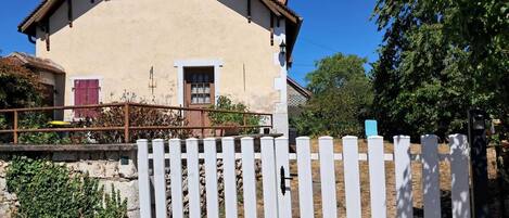 A house with a white picket fence, a brown roof, and a beige exterior.
