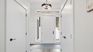 A hallway with white doors, a wooden floor, and a ceiling light fixture. - New 4 bed/3 bath, one level home - private hot tub, BBQ, garage & office (Silver Star Mountain)