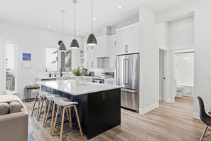 Una cocina moderna con una isla grande, electrodomésticos de acero inoxidable e iluminación colgante.