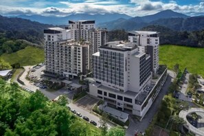 A multi-story hotel with a modern architectural design, surrounded by lush greenery and mountains in the background. - Studio V at Midhills Genting Highlands Free WiFi (Genting Highlands)