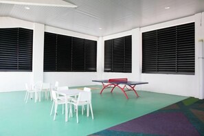 A room with a ping pong table, white chairs, and large windows with blinds. - Studio V at Midhills Genting Highlands Free WiFi (Genting Highlands)