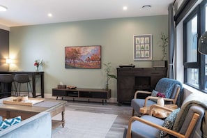 A living room with a sofa, a coffee table, a TV stand, and a fireplace.