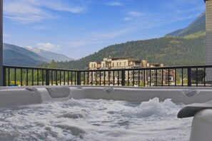 A hot tub with a view of a mountain and a building in the background.