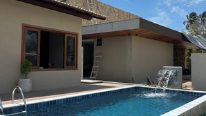 A modern house with a swimming pool, stone exterior, and a small waterfall feature. - Casamares beach in Ipioca, Maceió, Angra de Ipioca condominium, Hibiscus Beach Club (Maceió)