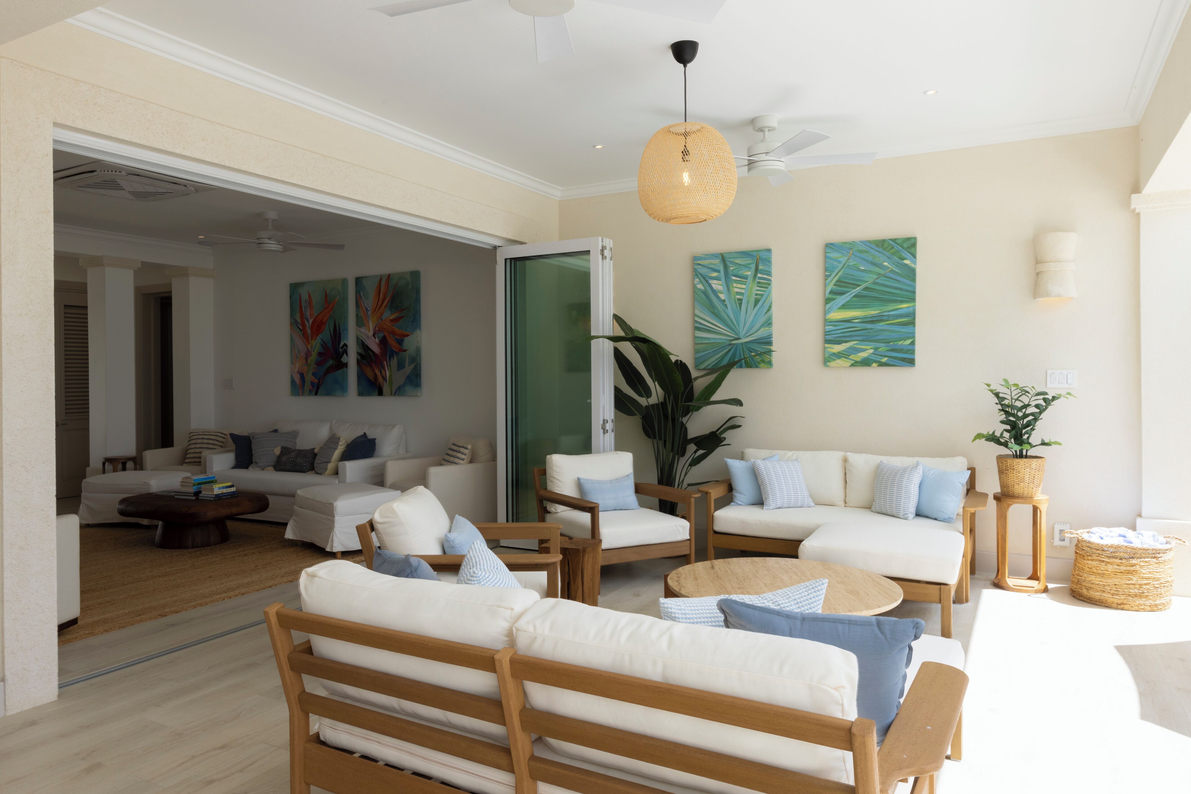 A spacious living area with a sofa set, wooden chairs, a coffee table, and a hanging light fixture.
