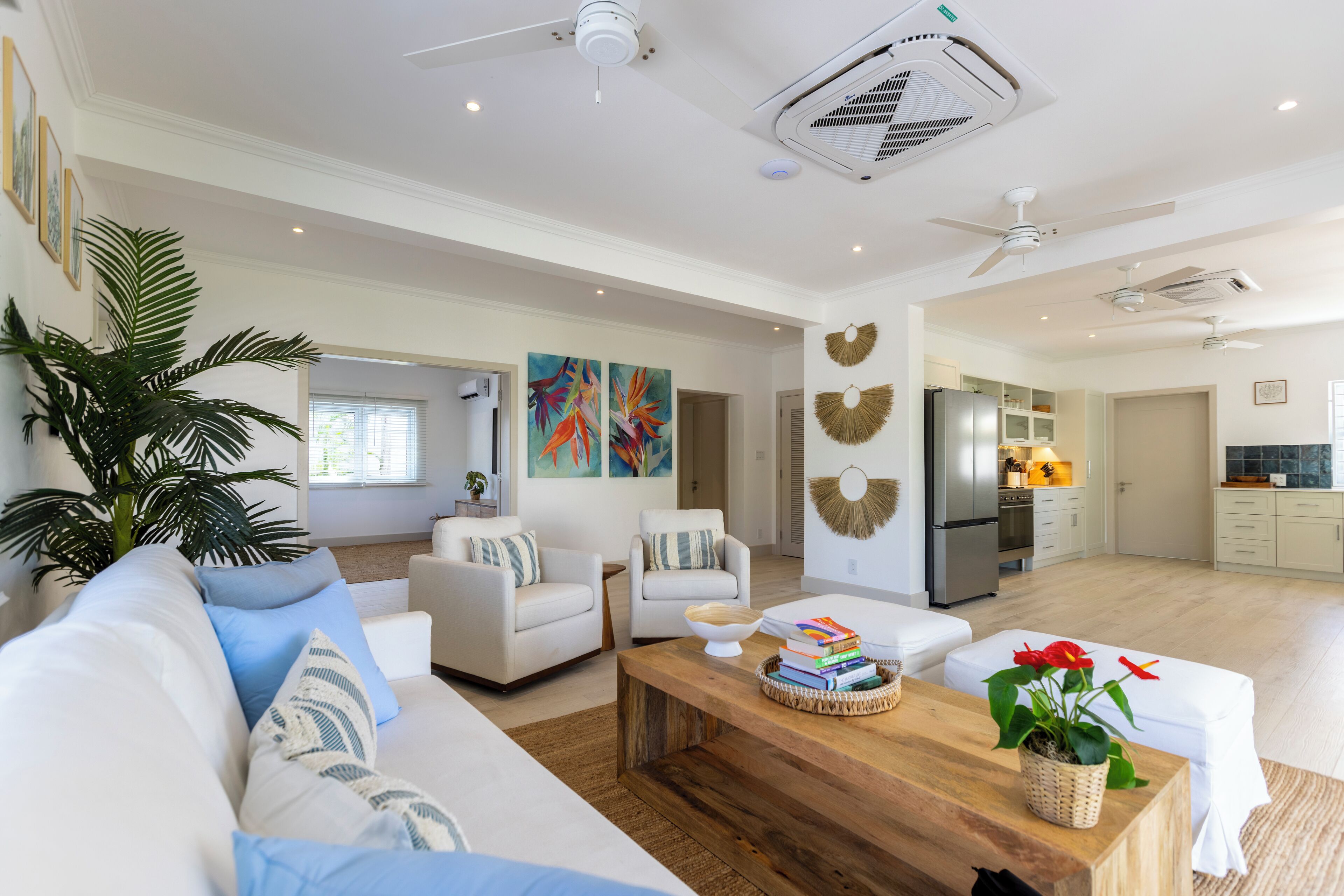 A spacious living area with a sofa, chairs, a coffee table, and a kitchen in the background.
