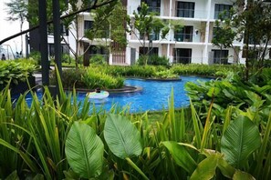 A pool surrounded by lush greenery, with a multi-story building in the background. - Urban Suite@Midhills Genting Highlands (Free WiFi) (Genting Highlands)
