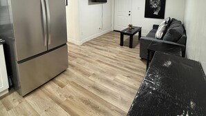 A compact living space with a kitchenette, a flat-screen TV mounted on the wall, a sofa, and a coffee table. - CB&M Westside Suites (Duchesne)