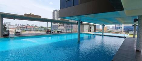 An indoor swimming pool with a city view, a covered area, and a modern architectural design.
