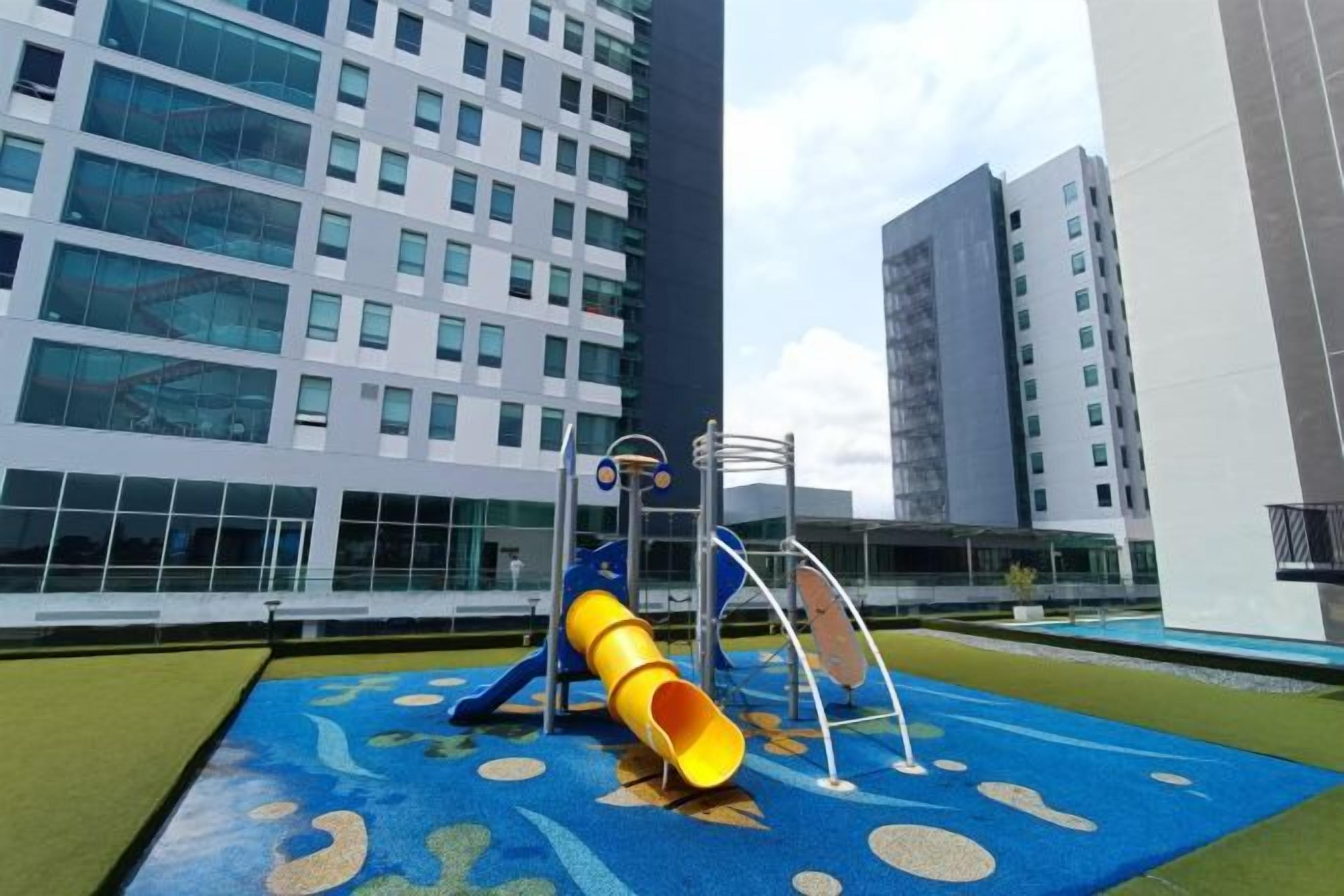 Ein Spielplatz mit Rutsche und Klettergerüsten vor moderner Architektur.