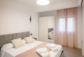 A modern bedroom with a bed, a wardrobe, and a window with curtains.