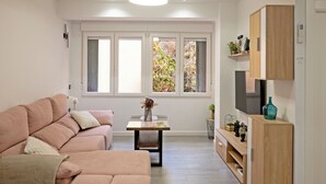Ett modernt vardagsrum med en soffa, ett litet bord och en tv som står på ett träskåp.