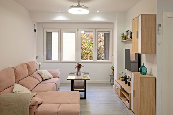 A modern living room with a sofa, a small table, and a TV on a wooden cabinet.
