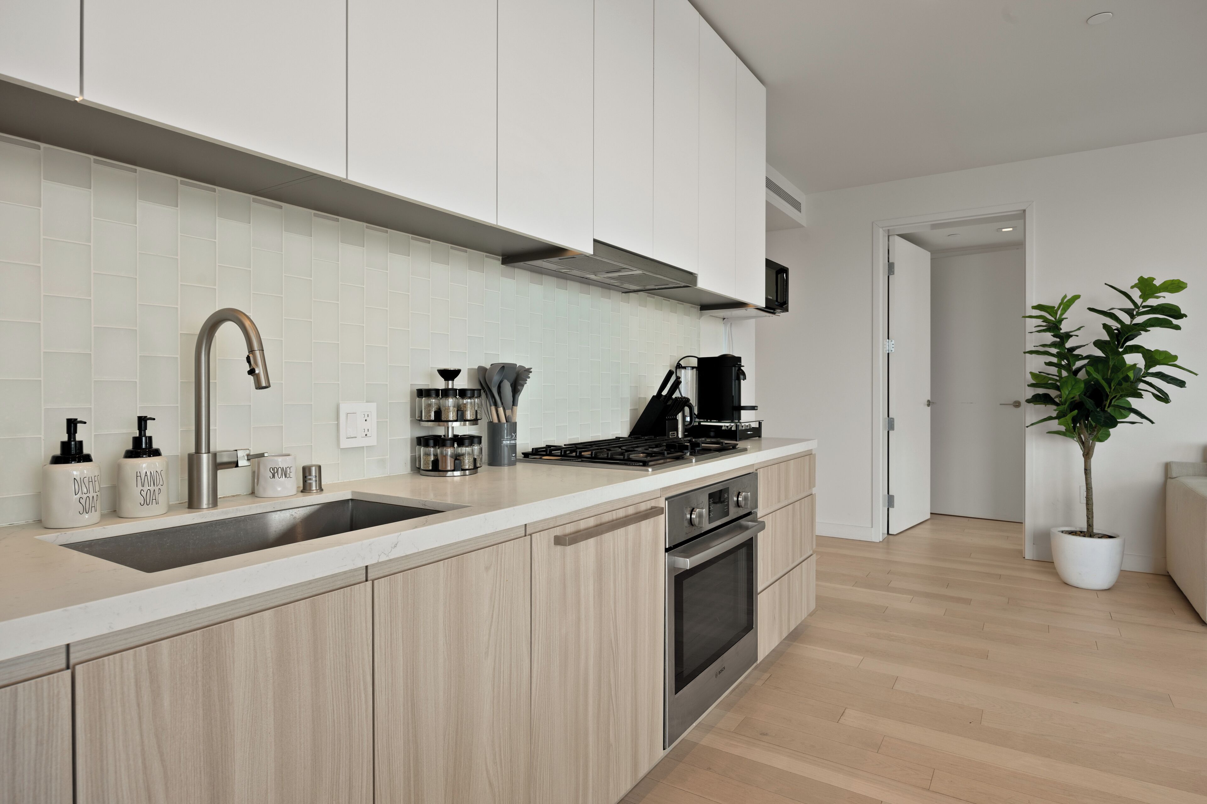 A modern kitchen with a stainless steel sink, a gas stove, and wooden cabinets.