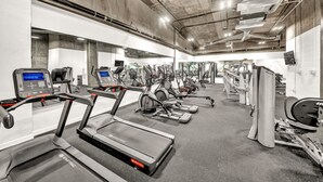 Un gimnasio con cintas de correr, máquinas elípticas y equipo de pesas.