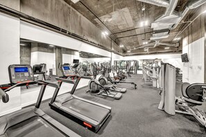 Un gimnasio con cintas de correr, máquinas elípticas y equipo de pesas.