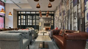 Un espace de détente moderne avec des canapés gris, un divan en cuir marron et une table basse centrale.