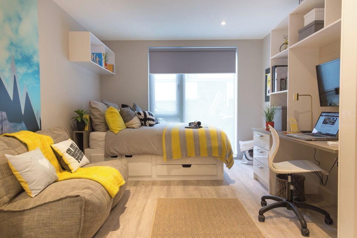 Un dormitorio moderno con una cama, un escritorio y una silla.