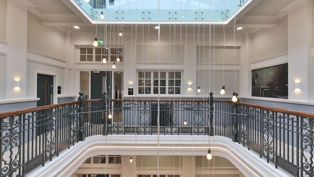 Un vaste espace intérieur doté d’un escalier central, de plusieurs niveaux et d’une verrière.