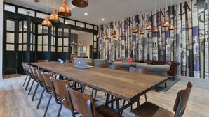 Une salle de conférence moderne, dotée d’une longue table en bois, de nombreuses chaises et de luminaires suspendus en cuivre.