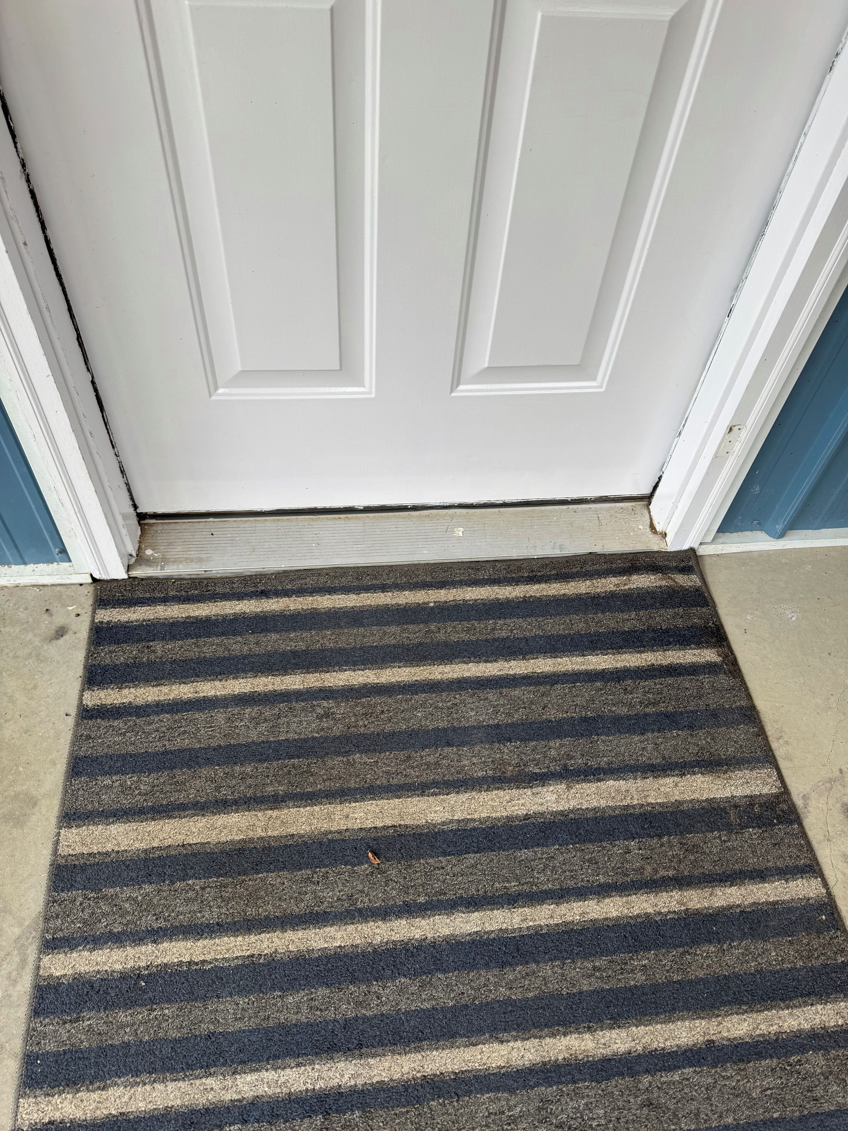 A striped doormat at a door entrance.
