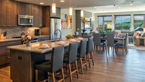 A modern kitchen with dark wood cabinets, stainless steel appliances, and a central island with bar stools. - Luxury 1-Bedroom Condo at Grand Colorado on Peak 8 — Ski-In/Ski-Out! (Breckenridge)