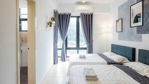 Ein modernes Hotelzimmer mit zwei Betten, einem großen Fenster mit Vorhängen, einer Klimaanlage und gerahmten Kunstwerken an der Wand.