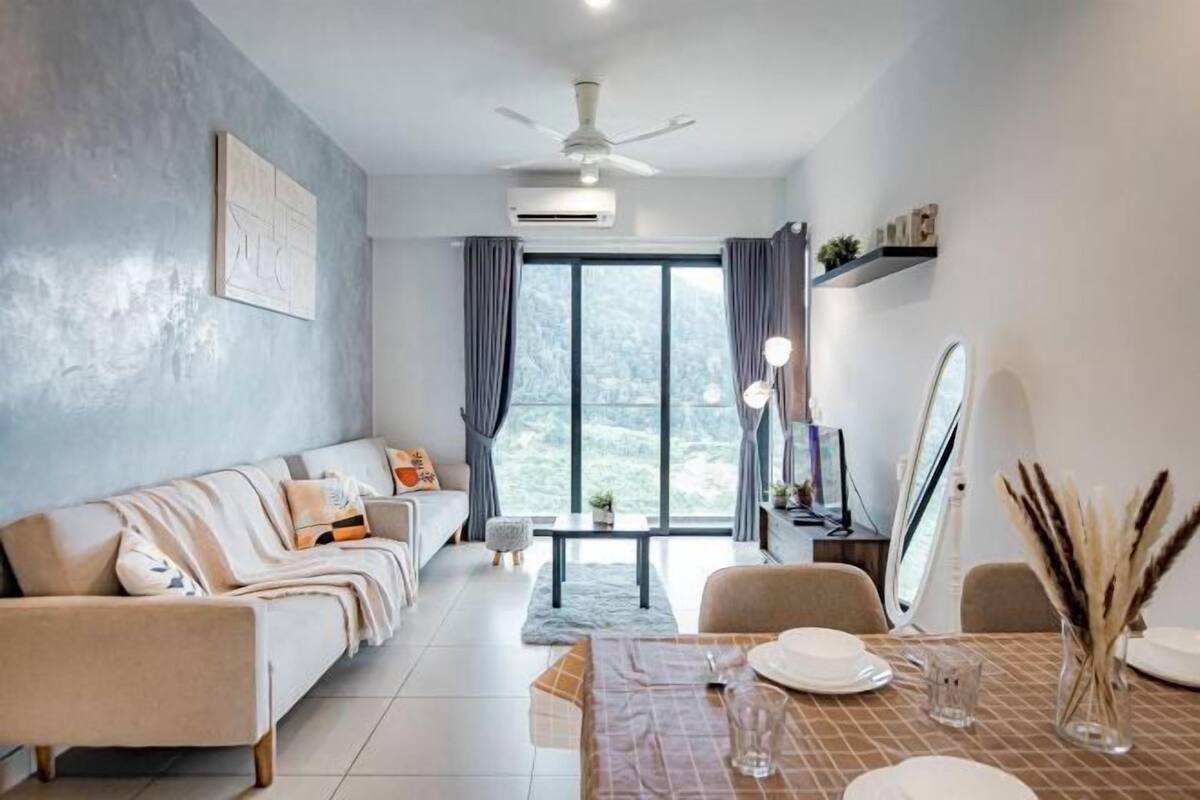 Un salón moderno con sofá, mesa de comedor y vista a un paisaje nevado a través de amplios ventanales.