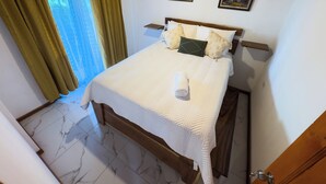 Un lit bien fait, avec une couette blanche, une serviette enroulée et des coussins décoratifs.