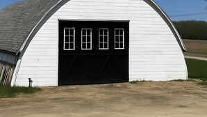 A white barn with a black door and three windows. - 8 Acre Lower-Level Hobby Farm Getaway (Prior Lake)