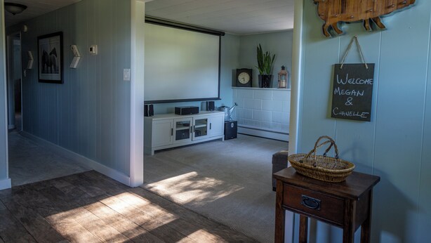 A hallway with a wooden floor, a white cabinet, a wicker basket, and a welcome sign on the wall. - 8 Acre Lower-Level Hobby Farm Getaway (Prior Lake)