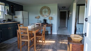 A kitchen with wooden cabinets, a dining table with chairs, a clock on the wall, and a staircase leading to another room. - 8 Acre Lower-Level Hobby Farm Getaway (Prior Lake)