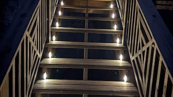 A wooden staircase with evenly spaced steps and handrails on both sides, leading to a door with a window.