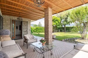 An outdoor patio with a stone wall, a wooden ceiling, and a glass table. - Entire condo in Trescore Balneario, Italy (Trescore Balneario)