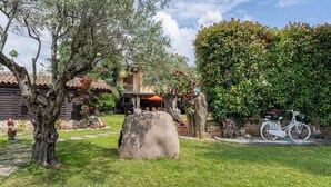 Una cabaña rústica con chimenea de piedra, una terraza de madera y una bicicleta estacionada al lado.